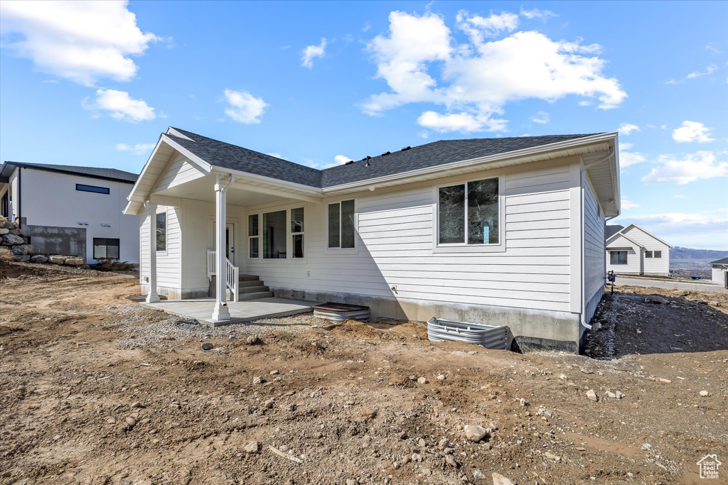 Rear view of house featuring a patio area and a shingled roof
