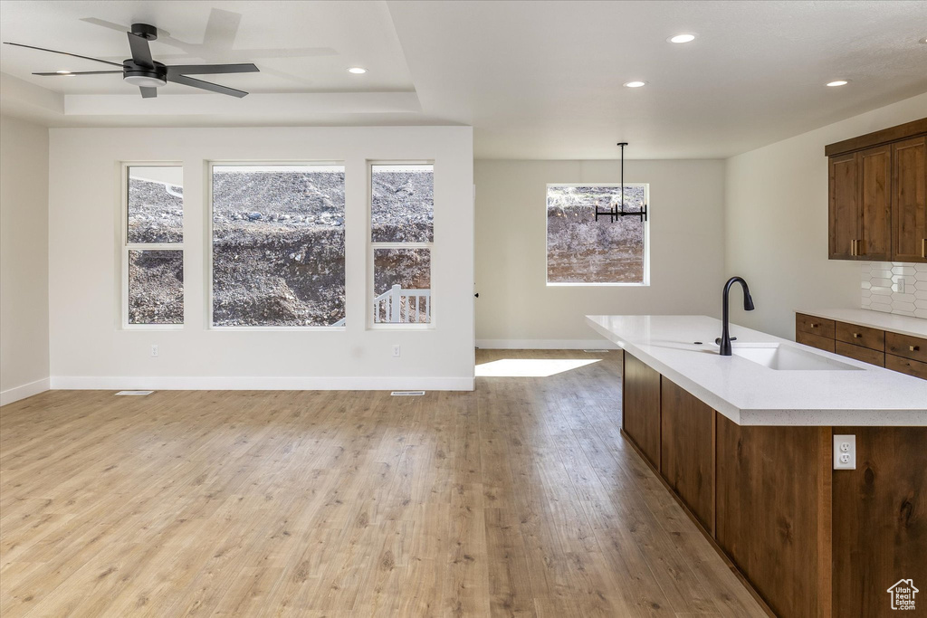 Kitchen with open floor plan, light countertops, light wood finished floors, recessed lighting, and a kitchen island with sink