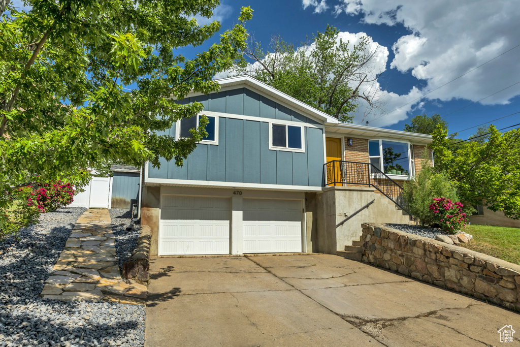 View of front of house with board and batten siding, a garage, concrete driveway, and brick siding