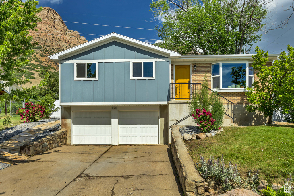 View of front of home with brick siding, a garage, concrete driveway, a front yard, and board and batten siding
