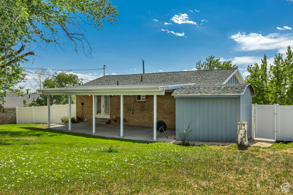 Rear view of property with a shingled roof, a fenced backyard, a gate, a patio, and french doors