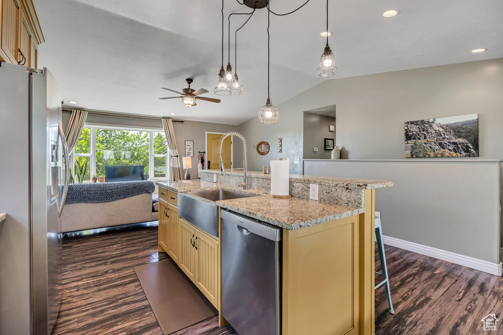 Kitchen featuring appliances with stainless steel finishes, open floor plan, dark wood-style floors, cream cabinets, and lofted ceiling