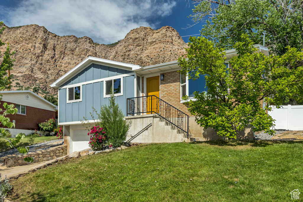 View of front of house featuring board and batten siding, a garage, brick siding, and a mountain view