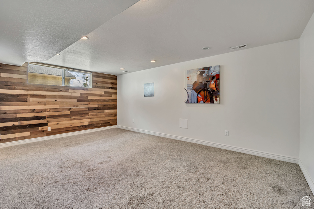Carpeted spare room featuring wood walls and recessed lighting