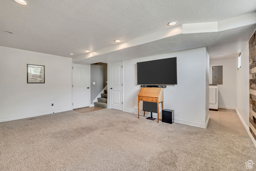 Finished below grade area featuring electric panel, washer / clothes dryer, light carpet, a textured ceiling, and recessed lighting