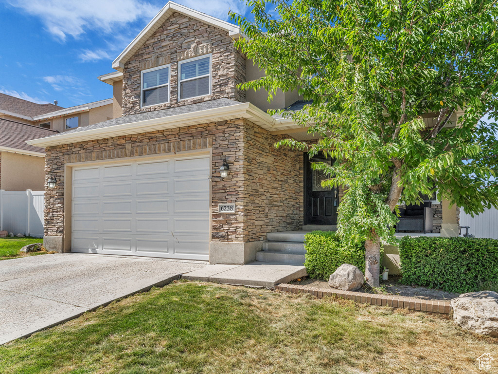 View of front of house featuring stone siding, driveway, a garage, and stucco siding