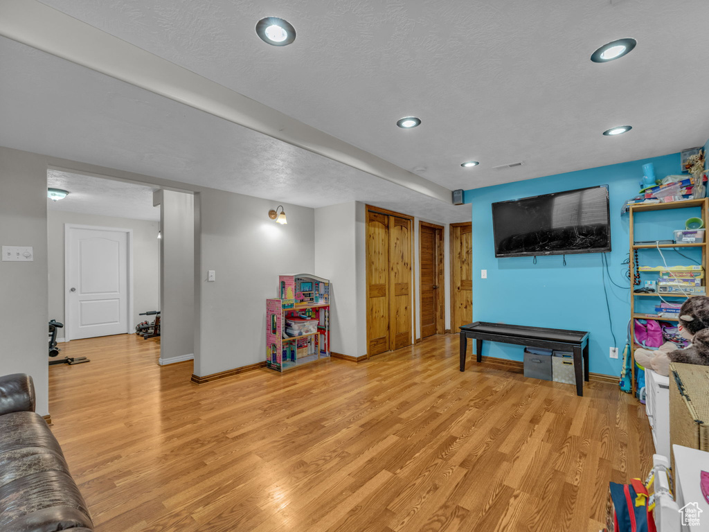 Recreation room featuring light wood-type flooring, recessed lighting, and a textured ceiling