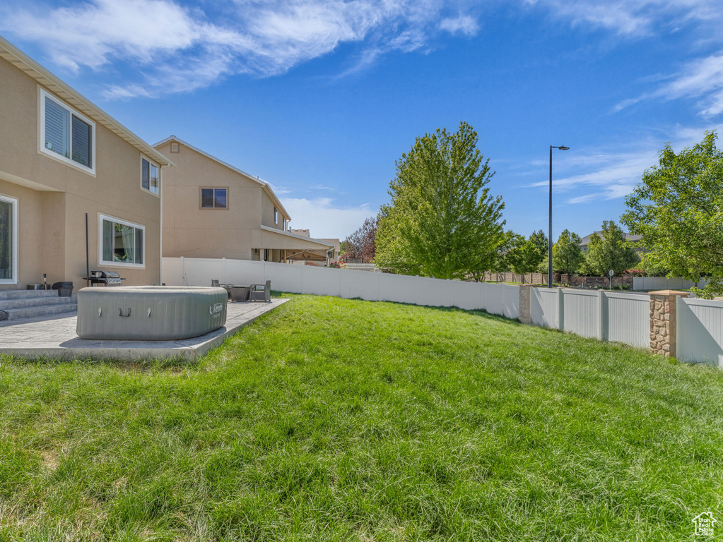 Fenced backyard featuring a patio area and a hot tub