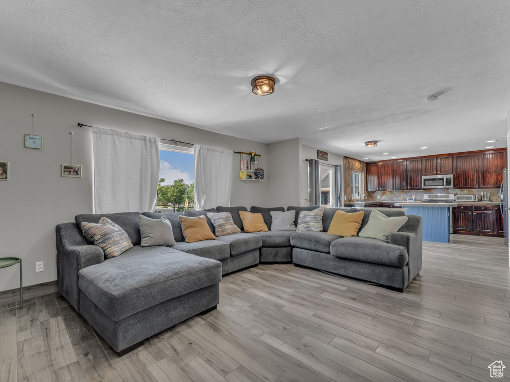 Living area featuring light wood finished floors, a textured ceiling, and recessed lighting