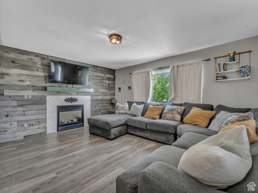 Living room with wooden walls, wood finished floors, a fireplace, and an accent wall