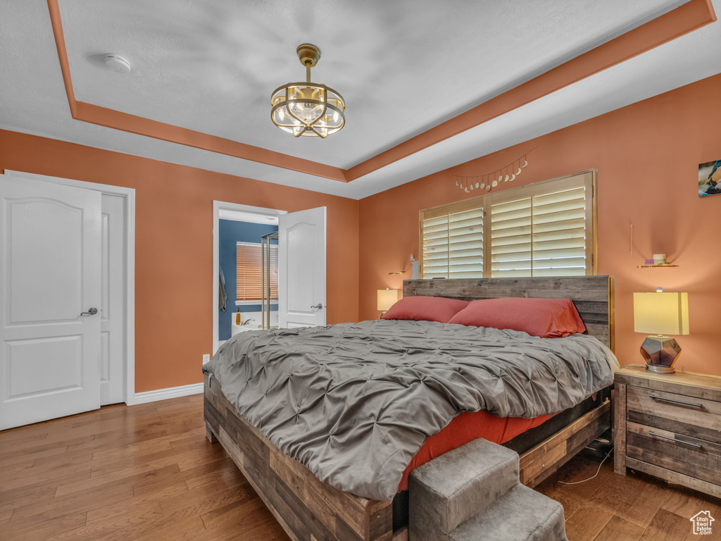 Bedroom featuring a tray ceiling, wood finished floors, and a chandelier