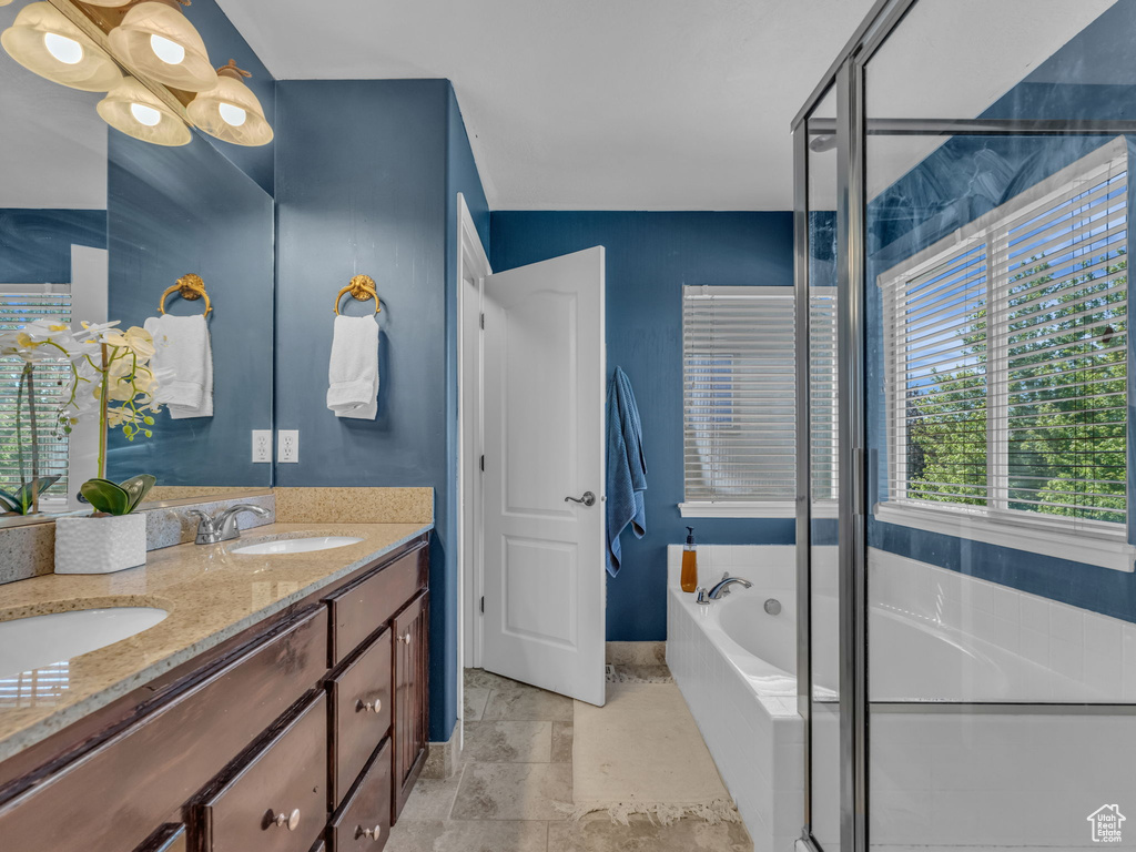 Bathroom with double vanity, a bath, and a shower with door