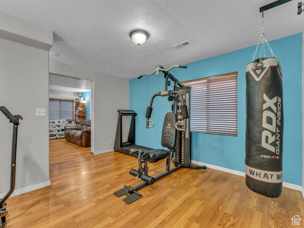 Exercise room featuring wood finished floors and a textured ceiling