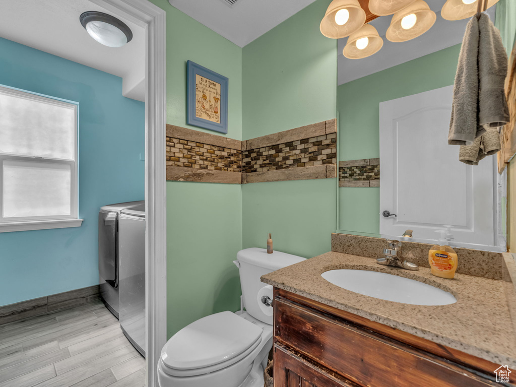 Bathroom with washing machine and dryer, vanity, wood finished floors, and a chandelier