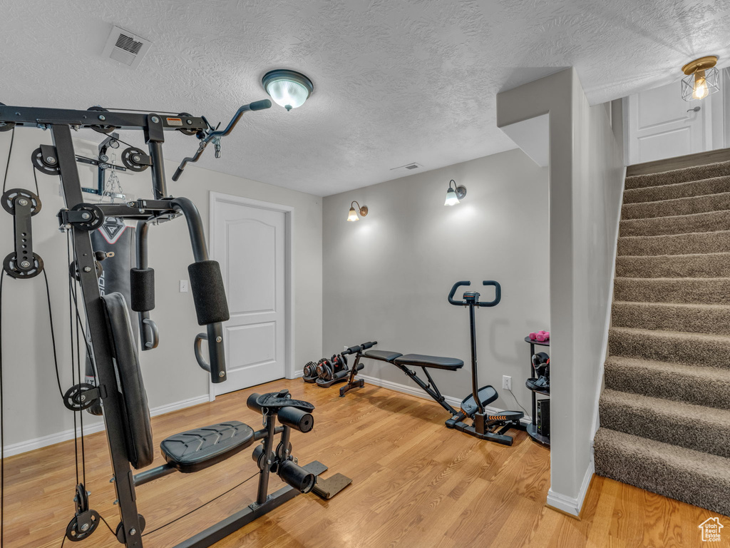 Workout room featuring light wood-style floors and a textured ceiling