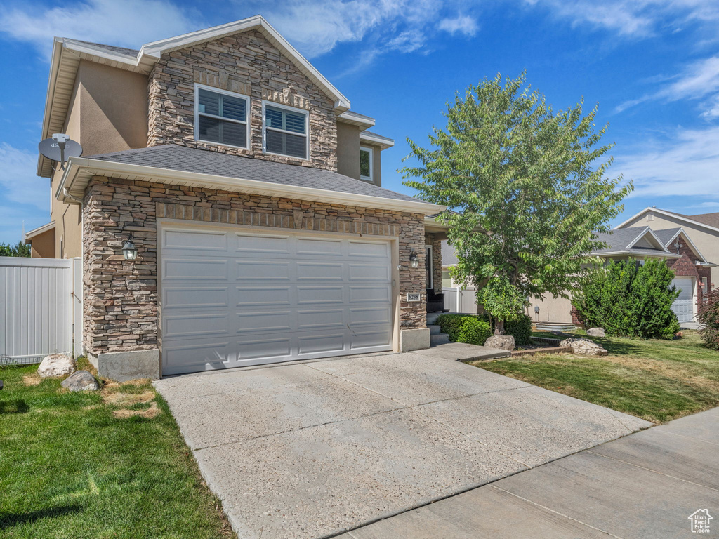 View of front of property featuring stone siding, concrete driveway, an attached garage, and stucco siding