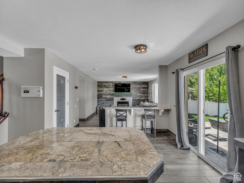 Kitchen featuring tile counters, a tiled fireplace, light wood-style flooring, and a textured ceiling