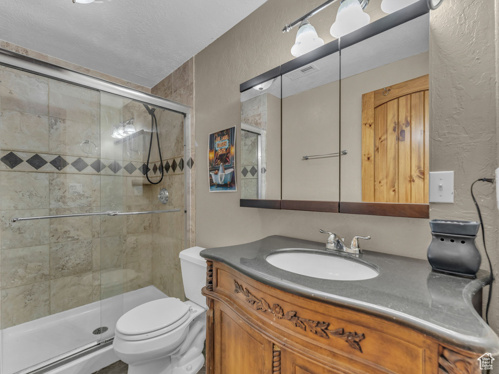 Full bathroom featuring a textured wall, vanity, and a stall shower