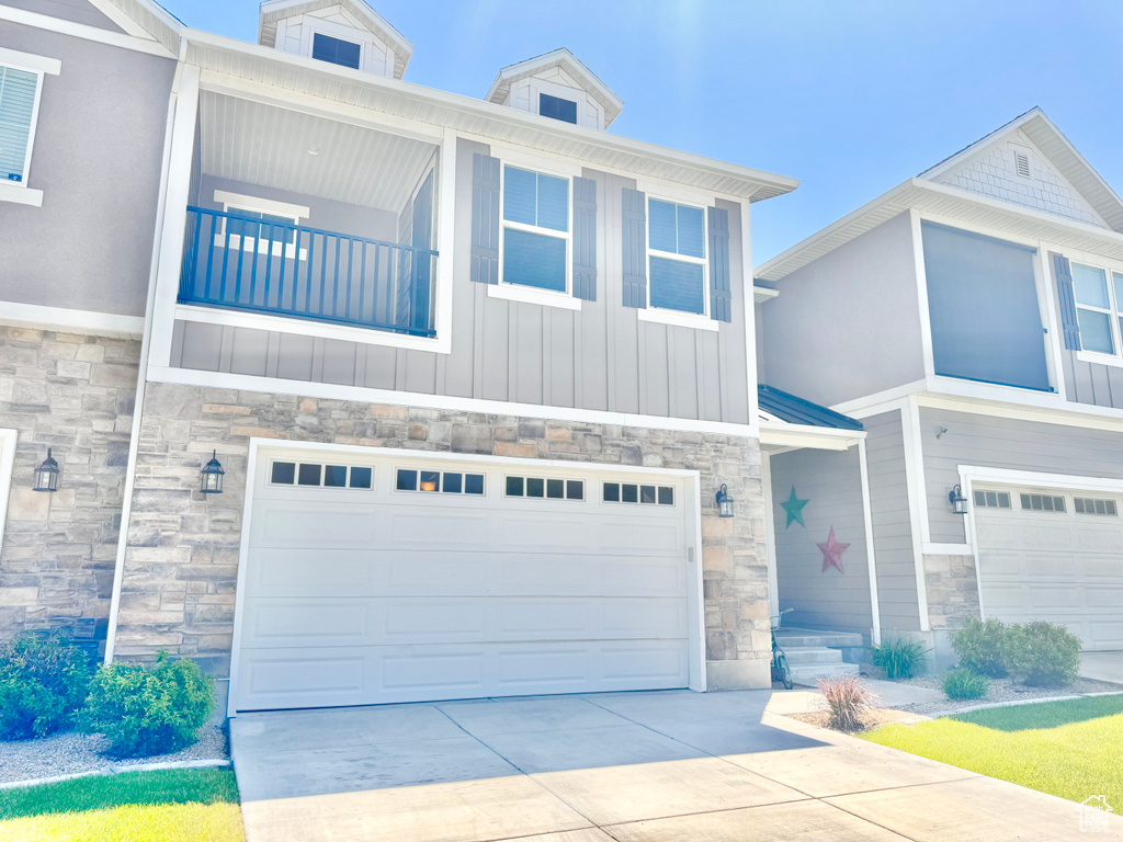 View of front of property featuring stone siding, an attached garage, driveway, and board and batten siding