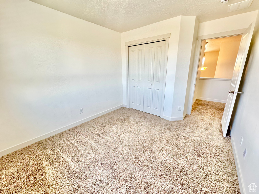 Unfurnished bedroom featuring light colored carpet and a closet