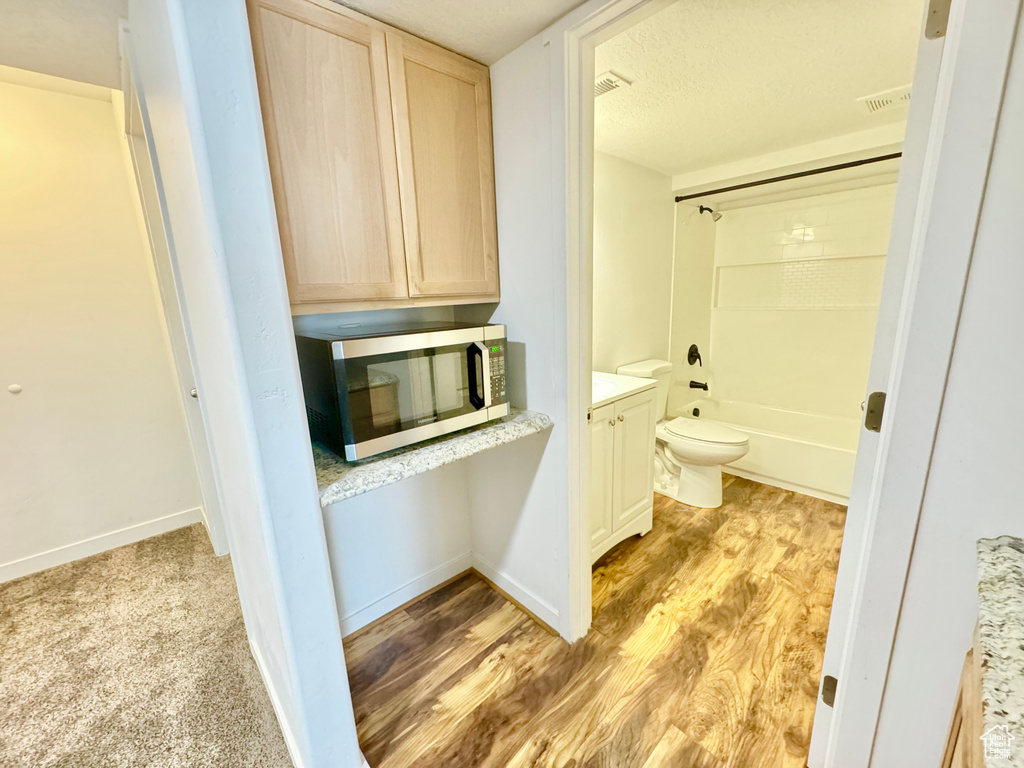 Full bathroom featuring vanity, wood finished floors, a textured ceiling, and bathing tub / shower combination