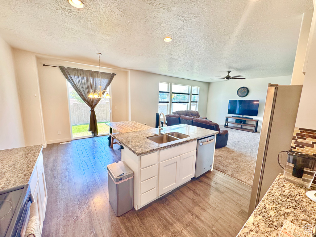 Kitchen with appliances with stainless steel finishes, open floor plan, a textured ceiling, white cabinetry, and wood finished floors