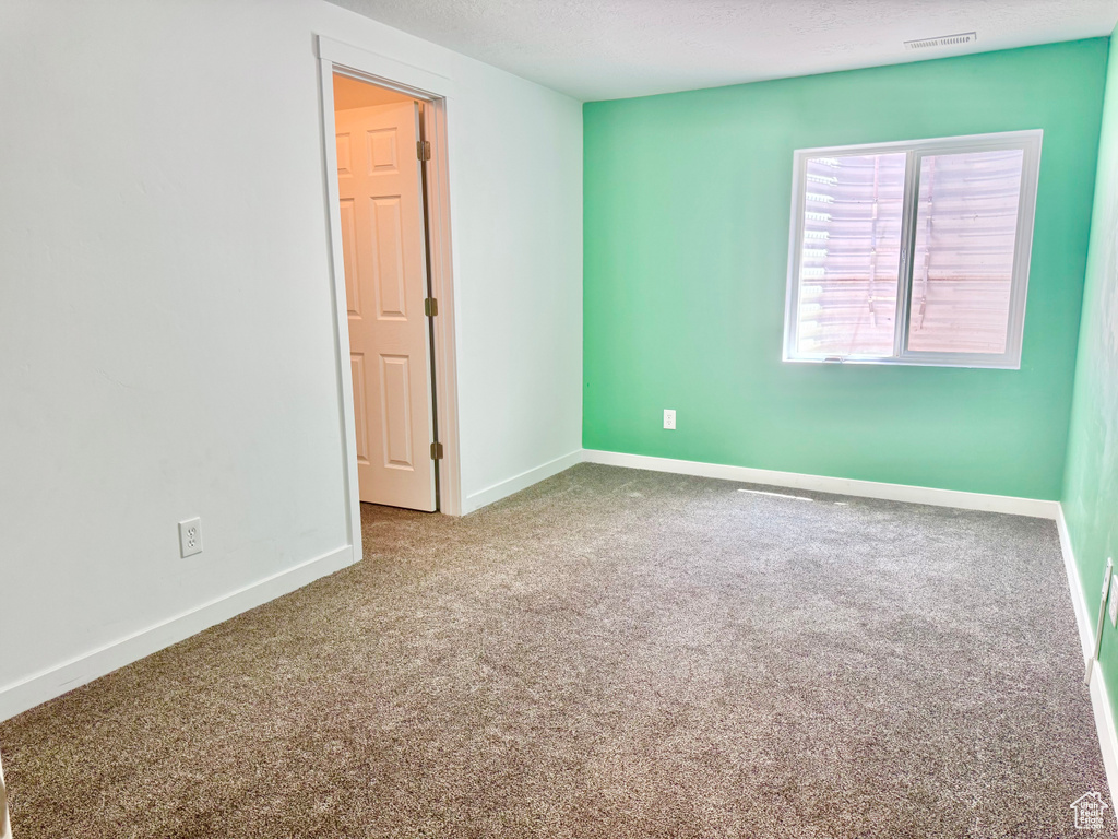 Carpeted spare room with baseboards and a textured ceiling
