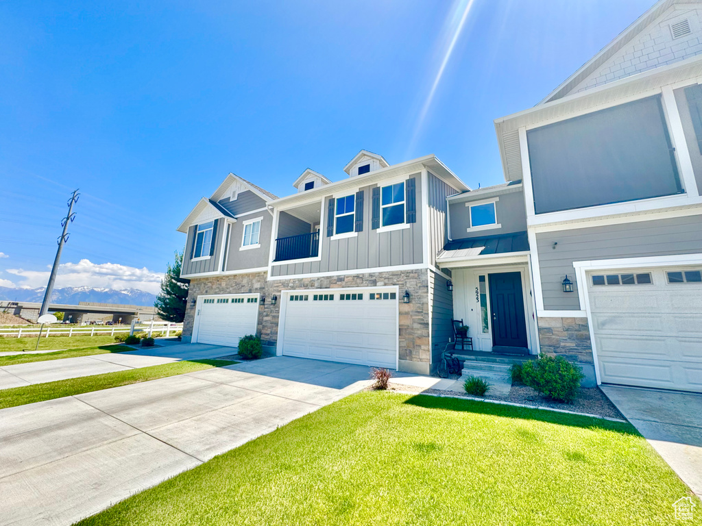 View of front of property featuring stone siding, a garage, driveway, and board and batten siding