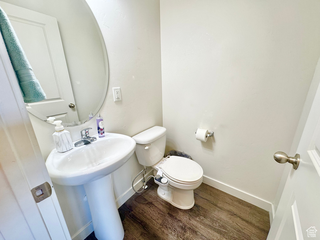 Half bath with wood finished floors and toilet