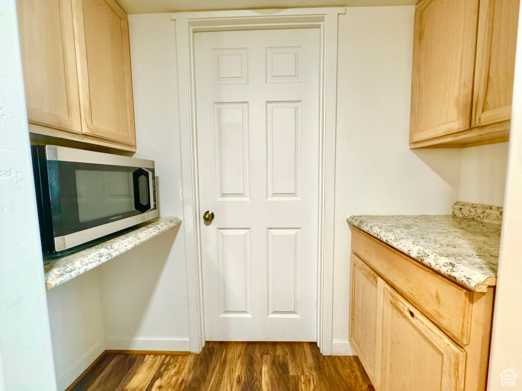Kitchen featuring stainless steel microwave, dark wood-style flooring, and light brown cabinets