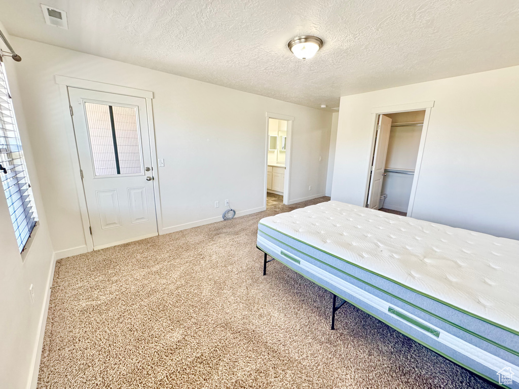 Carpeted bedroom with a textured ceiling, a closet, and ensuite bath