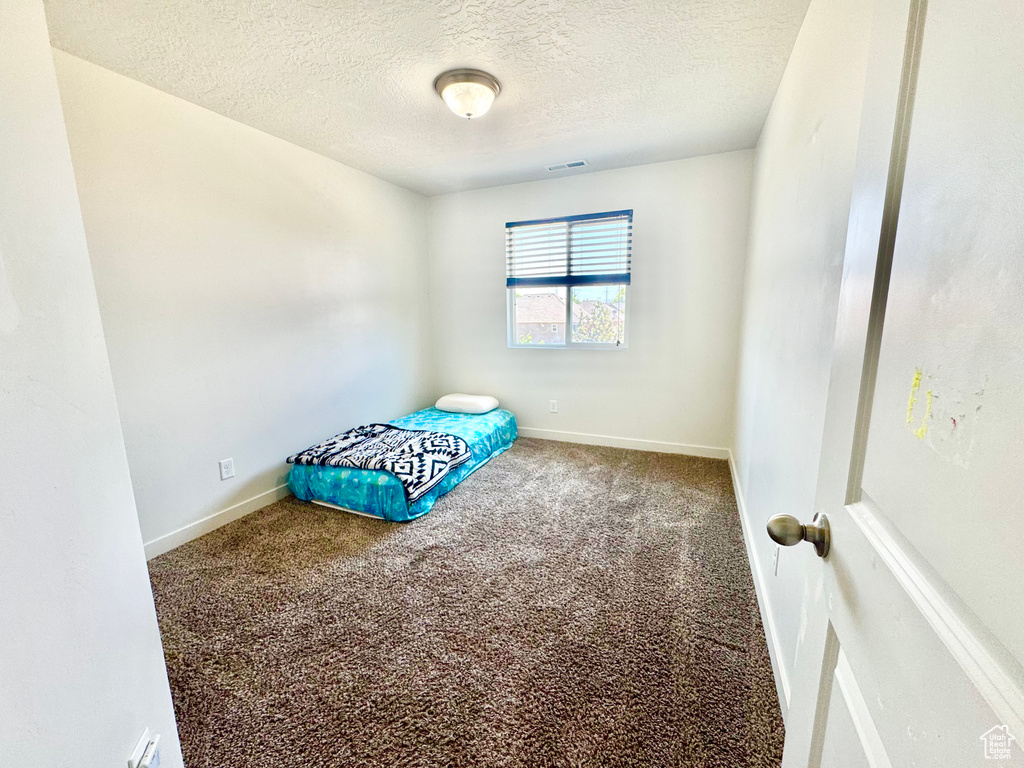 Unfurnished bedroom featuring a textured ceiling and carpet