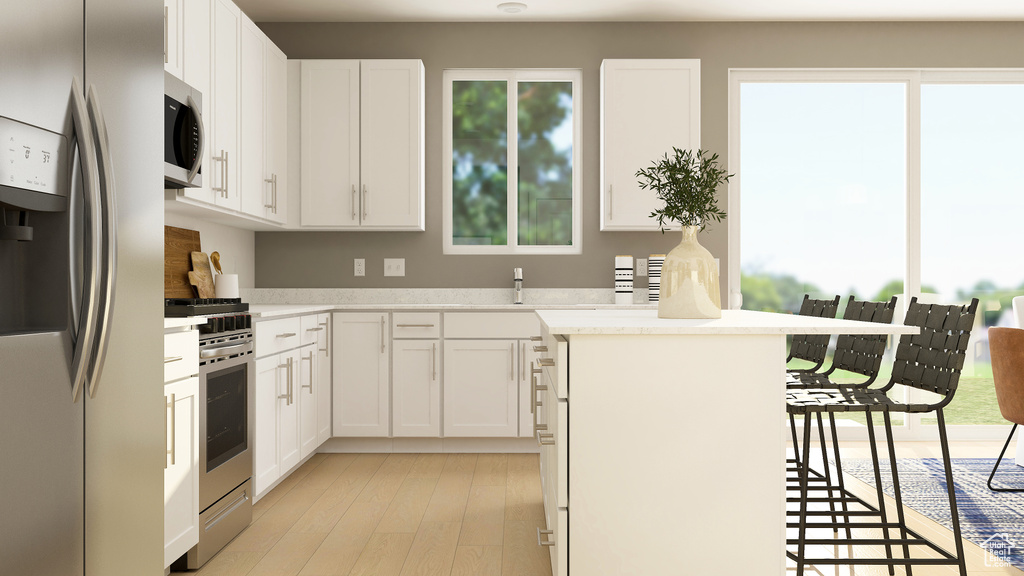 Kitchen with appliances with stainless steel finishes, light wood-type flooring, white cabinets, and light countertops