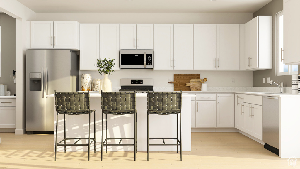 Kitchen featuring stainless steel appliances, light wood-style flooring, white cabinets, and a kitchen island