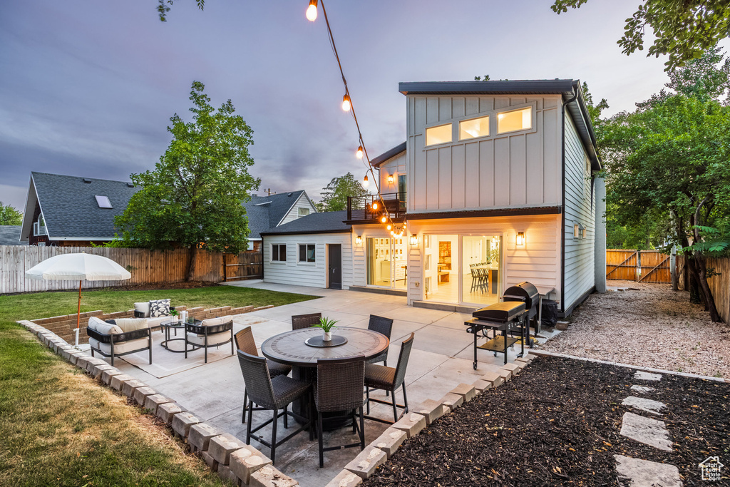 Rear view of house featuring board and batten siding, a patio, a fenced backyard, and an outdoor living space