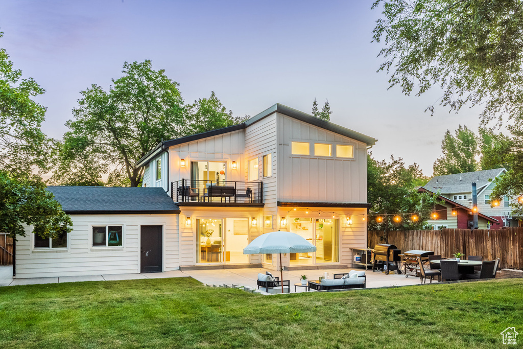 Back of property featuring a balcony, a patio, an outdoor hangout area, and board and batten siding