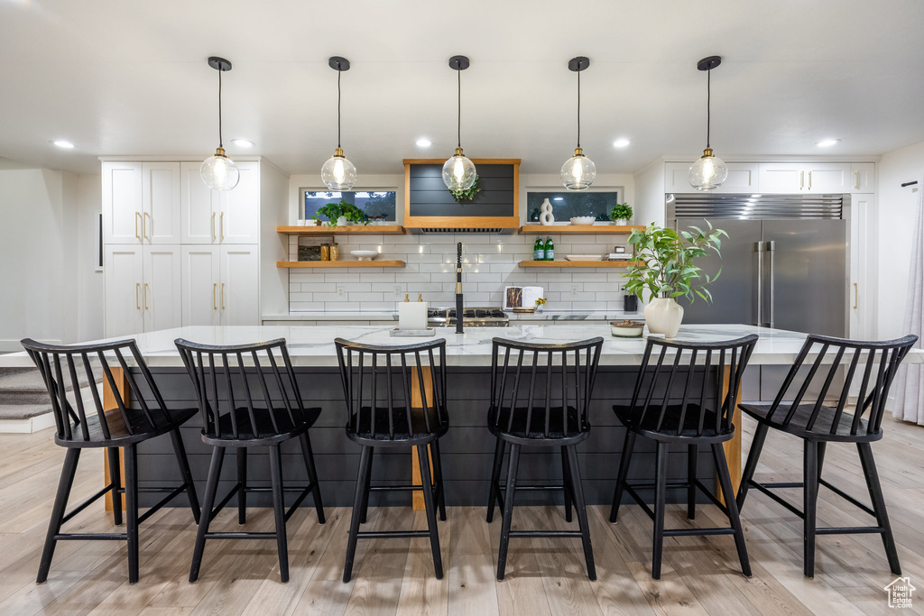 Kitchen with open shelves, built in fridge, backsplash, and white cabinetry