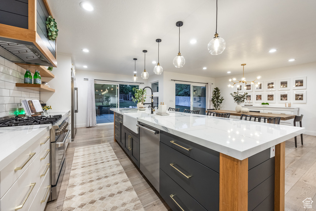 Kitchen with stainless steel appliances, recessed lighting, range hood, light wood-type flooring, and open shelves