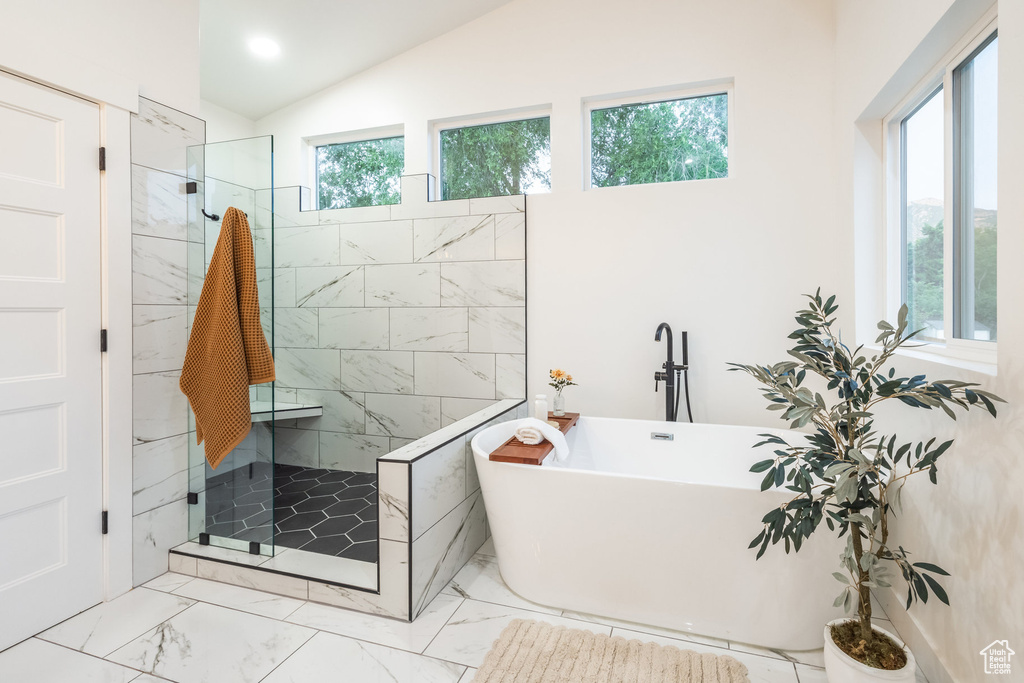 Full bathroom with marble look tile flooring, a soaking tub, a tile shower, and lofted ceiling