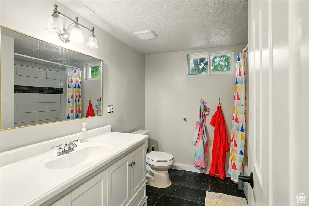 Full bathroom with vanity, a textured ceiling, and curtained shower