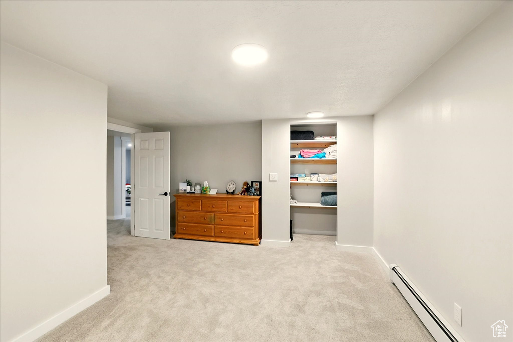 Finished basement with a baseboard radiator and light carpet