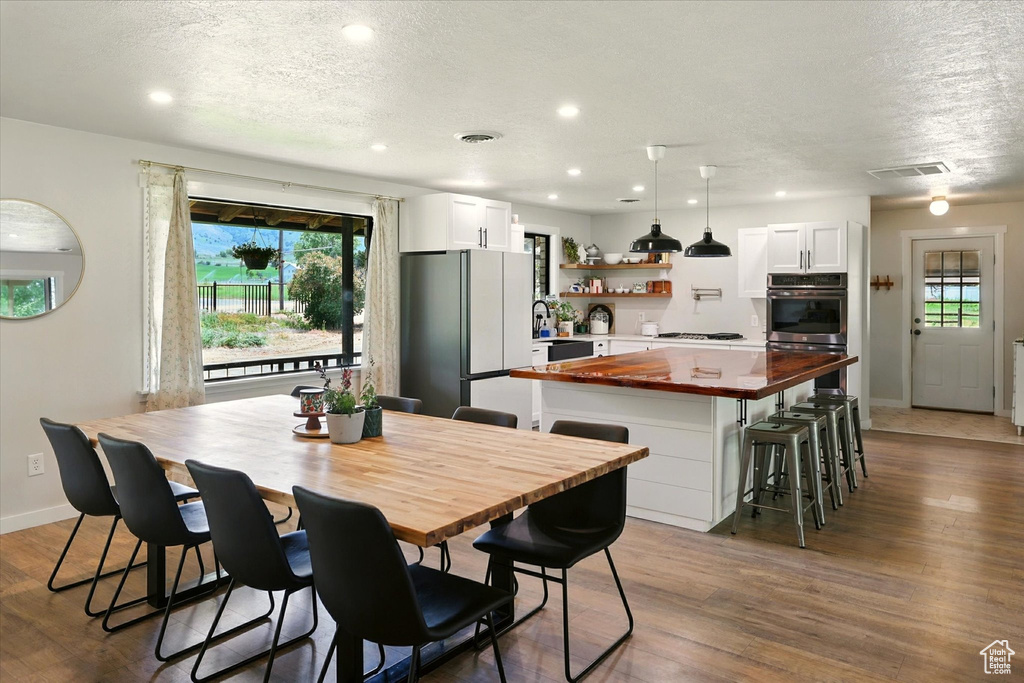 Dining room featuring a textured ceiling, dark wood-type flooring, plenty of natural light, and recessed lighting