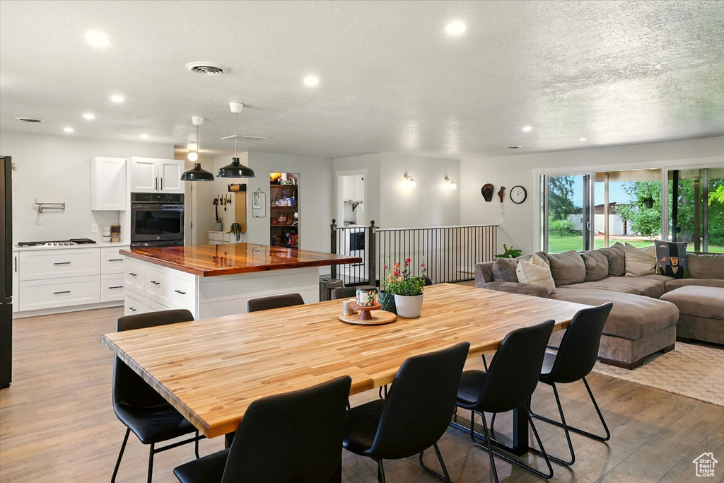 Dining room featuring recessed lighting, light wood-type flooring, and a textured ceiling