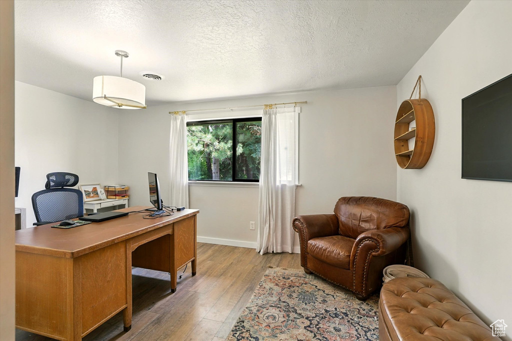 Office area featuring light wood-style flooring and a textured ceiling