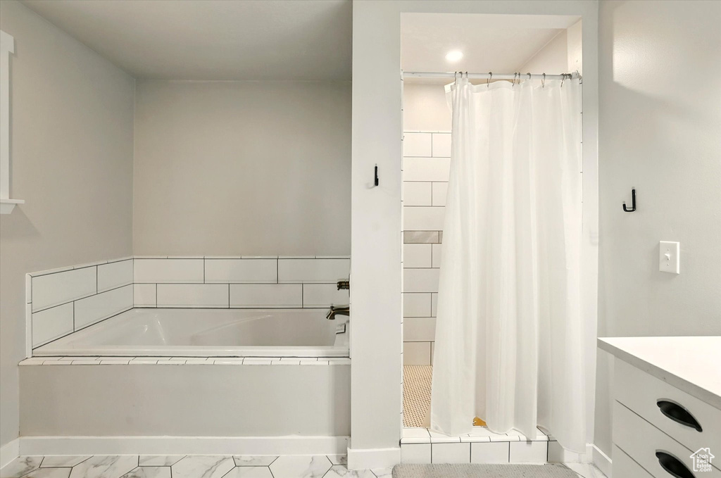 Full bathroom with a stall shower, a garden tub, marble look tile flooring, vanity, and recessed lighting