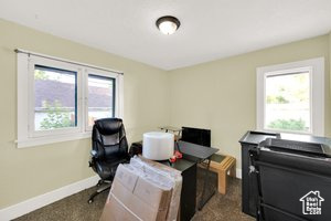 Office area with baseboards and dark colored carpet