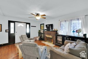 Living area featuring wood finished floors, a ceiling fan, and a fireplace