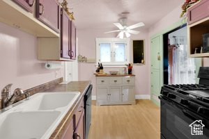 Kitchen featuring range with gas cooktop, a ceiling fan, light wood-type flooring, and light countertops