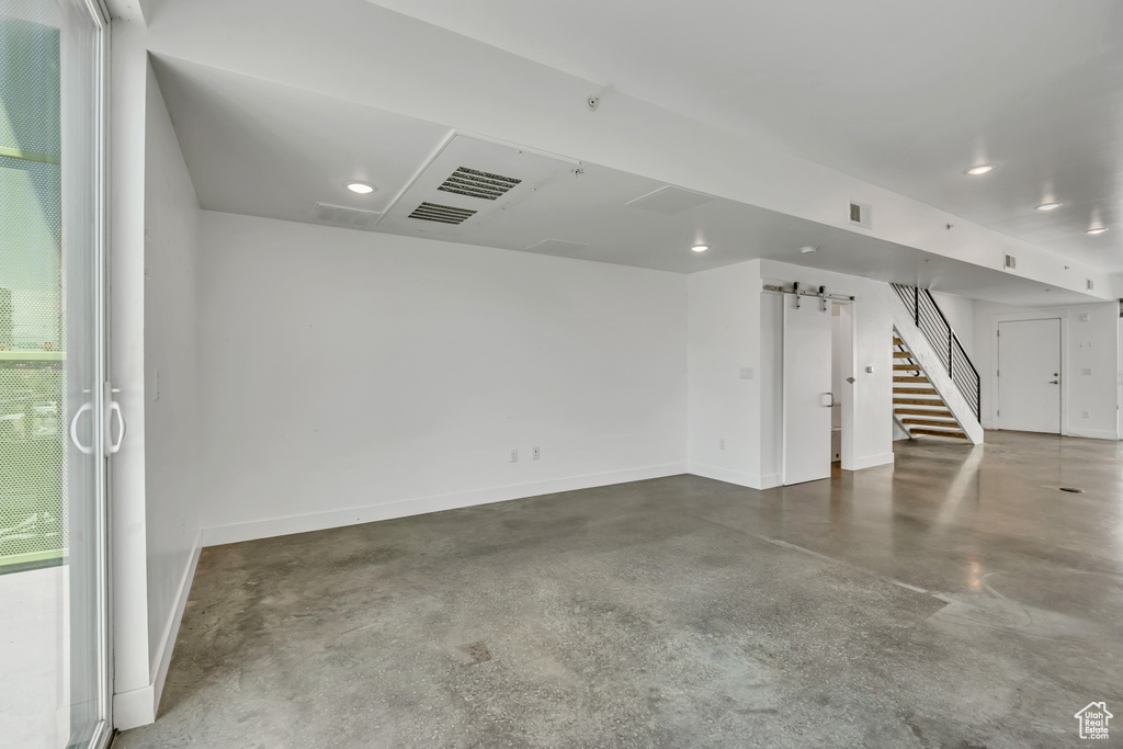 Additional living space featuring finished concrete flooring, stairs, recessed lighting, and a barn door