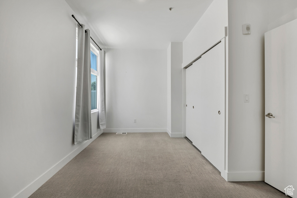 Unfurnished bedroom with light carpet and a closet